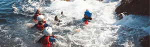 Participantes de coasteering nadando en las aguas turquesas de la costa de Ibiza