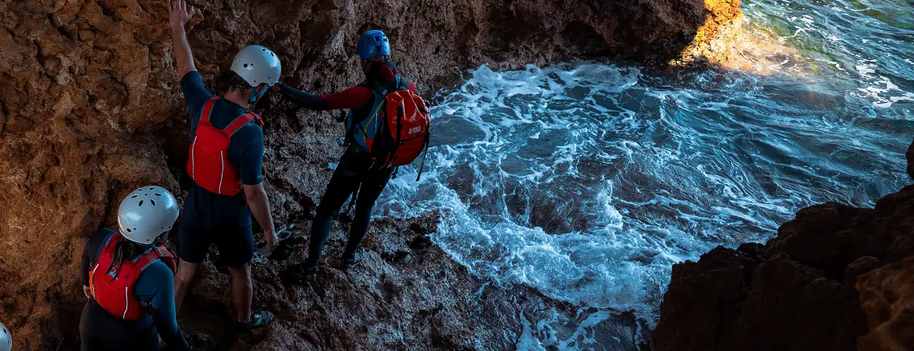 Group exploring a sea cave and swimming during a coasteering adventure in Ibiza.