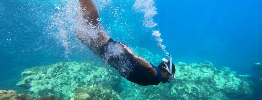 Man free diving with mask and snorkel exploring the rocky seabed and algae in the crystal clear waters of Ibiza